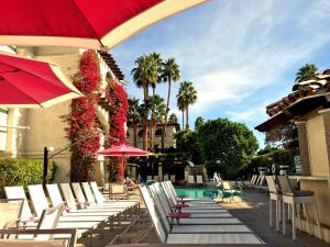 a group of chairs and umbrellas next to a pool at Best Western Plus Las Brisas Hotel in Palm Springs