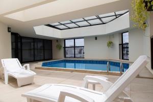 una piscina con sedie a sdraio bianche e una piscina di BEN - Flats Completos com Limpeza Diária e Estacionamento Incluso a San Paolo