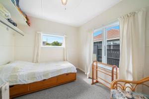 1 dormitorio con cama y ventana en The Green Trout - Paraparaumu Beach Holiday Home, en Paraparaumu Beach