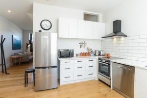 a kitchen with white cabinets and a stainless steel refrigerator at Studio 488 - Napier Holiday Apartment in Napier