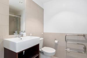 a bathroom with a white sink and a toilet at Rooftop Retreat - Mount Maunganui Holiday Home in Mount Maunganui