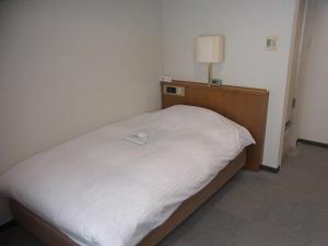 Una cama pequeña en una habitación con una lámpara. en Hotel New Mogamiya en Yamagata