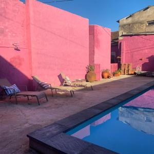 einen Pool mit zwei Stühlen und einer rosa Wand in der Unterkunft São Miguel House , Casa do Carvalhal in Santarém