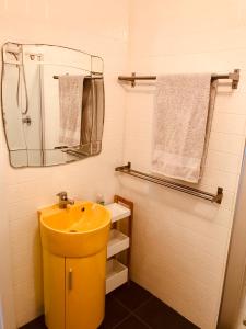 a bathroom with a yellow sink and a mirror at Ella May Holiday Flats in Tuross Heads