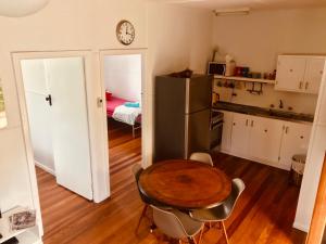 a kitchen with a table, chairs and a refrigerator at Ella May Holiday Flats in Tuross Heads