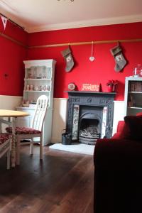 een woonkamer met rode muren en een open haard bij Ellenboro House Bed & Breakfast & self-catering in Cartmel