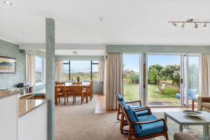 eine Küche und ein Wohnzimmer mit einem Tisch und Stühlen in der Unterkunft La Casa de la Playa - Beachfront Waikanae Home in Waikanae