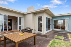 eine Terrasse mit einem Holztisch vor einem Haus in der Unterkunft La Casa de la Playa - Beachfront Waikanae Home in Waikanae