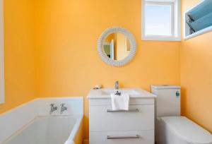 a bathroom with a sink and a toilet and a mirror at La Casa de la Playa - Beachfront Waikanae Home in Waikanae