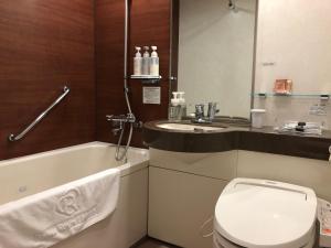 a bathroom with a toilet and a sink and a bath tub at Daiwa Roynet Hotel Oita in Oita
