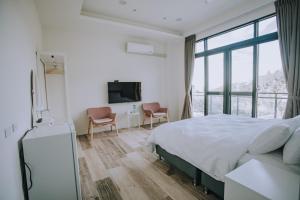 Schlafzimmer mit einem Bett, einem Schreibtisch und einem TV in der Unterkunft Ruili Tea Villa in Meishan