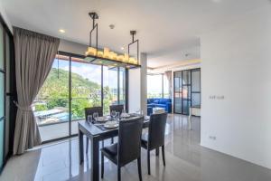 a dining room with a table and chairs and a large window at 2BDR Apartment near Surin beach #703 in Surin Beach