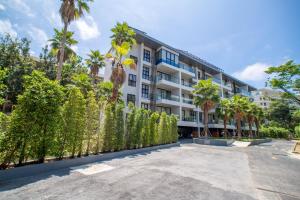 a building with palm trees and a fence at 2BDR Apartment near Surin beach #703 in Surin Beach