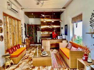 a living room with couches and a woman in the background at Veda5 Ayurveda & Yoga Retreat in Rishīkesh