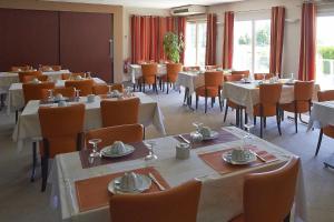 un comedor con mesas, sillas y ventanas en Cit'Hotel Les Alizés en Limoges