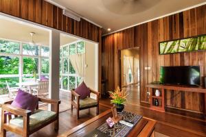 a living room with wood paneling and a flat screen tv at Sutera Sanctuary Lodges At Poring Hot Springs in Ranau