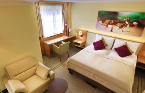 ein Hotelzimmer mit einem Bett und einem Stuhl in der Unterkunft Hotel Leobersdorfer Hof in Leobersdorf