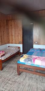 Duas camas num quarto com paredes de madeira em Vamoose Shri Ganesh Homestay em Māngwa