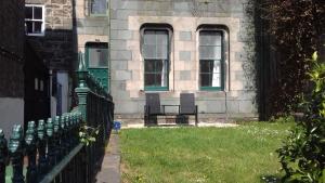 a fence in front of a building with two windows at Ground Floor Barmouth Centre Apartment With Garden in Barmouth