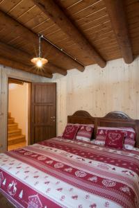 um quarto com uma cama grande com lençóis vermelhos e brancos em Baita Mirellina - Case di Viso em Ponte di Legno