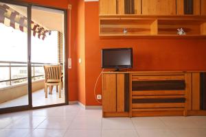a living room with a television and a balcony at AT031 Comunidad con 2 piscinas, a 5 min a pie de la playa in Torredembarra