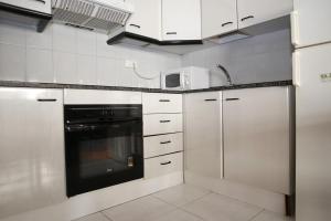 uma cozinha com armários brancos e um aparelho preto em AT031 Les Dunes em Torredembarra