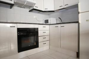 a kitchen with white cabinets and a black appliance at AT031 Comunidad con 2 piscinas, a 5 min a pie de la playa in Torredembarra