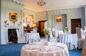 a dining room with white tables and chairs and a fireplace at Llangoed Hall in Bronllys