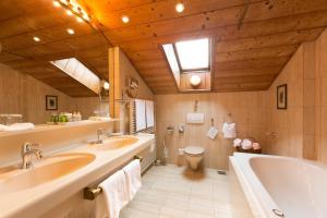 ein Badezimmer mit zwei Waschbecken, einer Badewanne und einem WC in der Unterkunft Reindl's Partenkirchener Hof in Garmisch-Partenkirchen