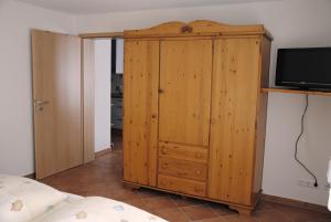 Cette chambre comprend une armoire en bois et une télévision. dans l'établissement Rothaarnest, à Winterberg