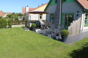 un patio con sillas y una sombrilla en Strandperle 264 mit Sauna und Kamin, en Julianadorp