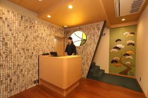 a man standing at a reception desk in a room with a wall at Hotel Matsunoi in Tokyo