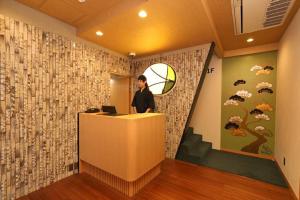 un homme debout à la réception dans une pièce avec un mur dans l'établissement Hotel Matsunoi, à Tokyo