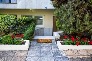 a garden with red flowers and plants in front of a building at Xsoma Flats "Coral" in Thessaloniki