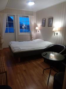 a bedroom with a bed and a table and two windows at Dalselv hotell in Stien