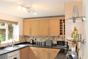 a kitchen with wooden cabinets and a black counter top at Homely and Budget Friendly 3 bed house Sleeps 6 Free Parking! in Milton Keynes