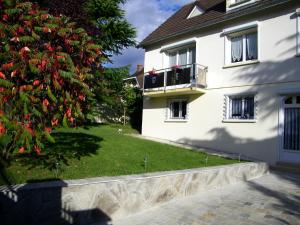 Una casa blanca con un árbol delante. en Grand appartement dans villa avec parking quartier résidentiel, en Joigny