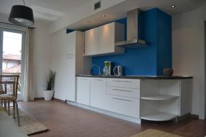 een keuken met witte kasten en een blauwe muur bij Casa Conte in Colico