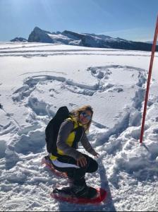 a woman is sitting on a snowboard in the snow at Bella Vista in Canale San Bovo