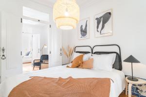 a bedroom with a large white bed with a chandelier at Casa Boma Lisboa - Typical and Spacious Apartment - Lapa II in Lisbon