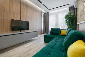 Il comprend un salon doté d'un canapé vert et d'une télévision à écran plat. dans l'établissement Royal VIP Apartment on Pidmurna 24, à Lviv