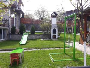 a yard with a swing set and a clock tower at Вила Багрянови in Dospat