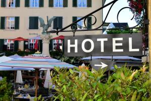 un panneau d'hôtel et un parapluie en face d'un hôtel dans l'établissement Romantik Hotel Schwan, à Horgen