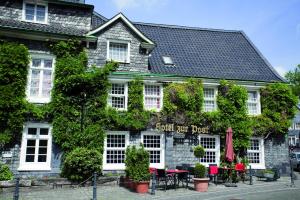 un edificio con mesas y sillas delante de él en Hotel Gräfrather Hof, en Solingen