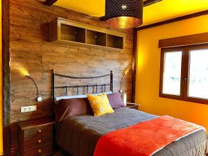 1 dormitorio con 1 cama y pared de madera en Naturbabia, en San Emiliano