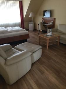 a hotel room with a bed and a couch and a table at BEST LONGSTAY INN, homestead and extended stay - KRAL Hotels Erlangen in Erlangen