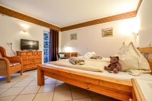 a teddy bear sitting on a bed in a bedroom at Hotel Landhaus Krombach in Elkenroth