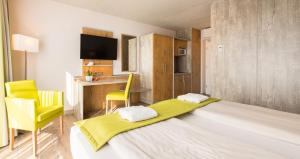 a bedroom with a large bed with yellow chairs and a desk at OHO Rooms Herrenberg Digital Access Only in Gäufelden