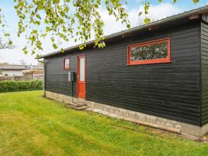 ノーポにある6 person holiday home in Nordborgの赤い扉と庭のある黒い家
