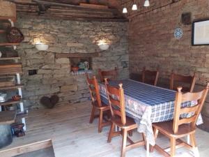 a dining room with a table and chairs and a stone wall at Къща Чалъкови in Tryavna